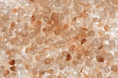 Aydınlatılmış pembe tuzun açık arkaplandaki makro görüntüsü hassas renklerde karmaşık kristal yapılar sergiliyor.