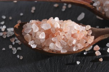 İki tahta kaşık pembe tuzla doludur.