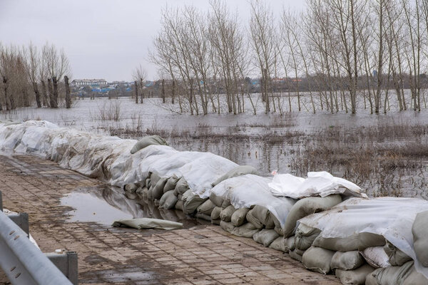 Stacks of sandbags are laid out on the sidewalk to protect against flooding