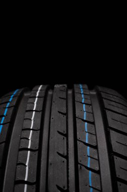 Car tires on black background, closeup of tread, selective focus clipart
