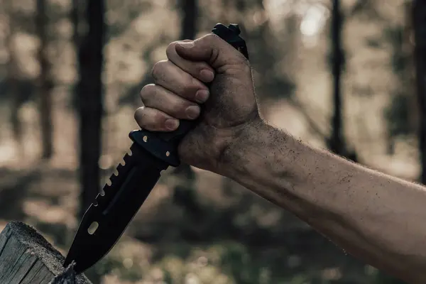 Hand man with hunting knife for survival in the forest. Concept recreation and survival in forest