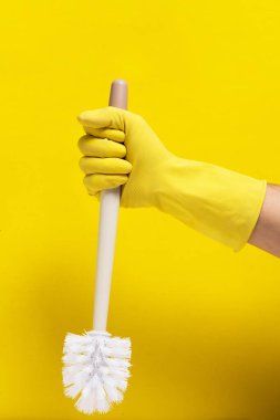 El sarısı lastik eldiven tuvalet temizleme fırçası sarı arka plan tutar