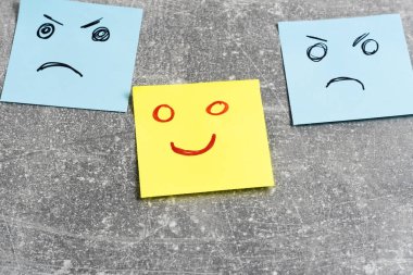 Gri arkaplandaki yapışkan notlarda duygusal gülen yüzler, yakın plan