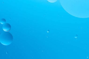 Açık mavi arkaplanda çeşitli boyutlarda mavi baloncuklu soyut resim, sakin ve minimalist görünüm oluşturur