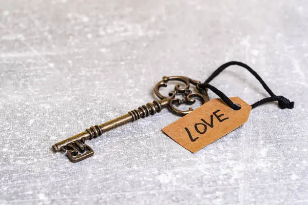 stock image Key to love and a tag with the word love on a gray background