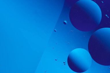 Koyu mavi arka planda süzülen mavi ve mor baloncuklu soyut görüntü, sakin ve minimalist bir görsel etki yaratıyor