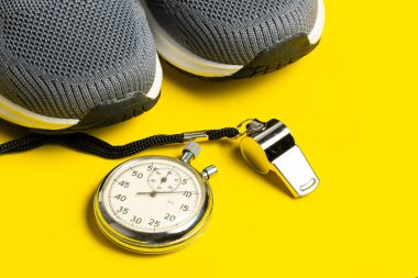 Spor malzemeleri ve sarı arka planda ıslık. Sağlıklı yaşam tarzı kavramı