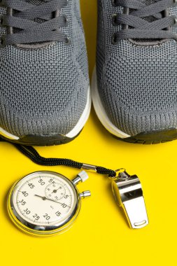 Spor ayakkabılar, kronometre ve sarı arka planda ıslık. Spor konsepti