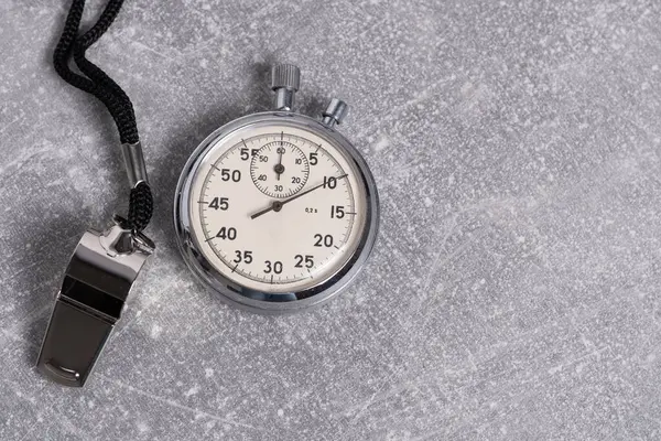 stock image Old stopwatch on gray stone background with whistle