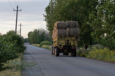 Kırsal bölgedeki kırsal yolda saman balyalarıyla dolu bir traktör.