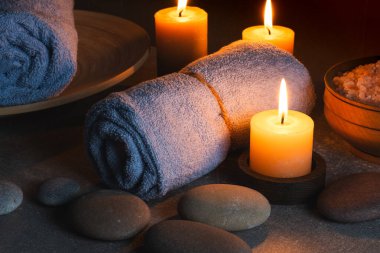 Havlular, mumlar ve karanlık arka planda deniz tuzu olan bir spa.