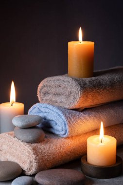 Havluları, mumları ve karanlık arka planda taşları olan bir spa.