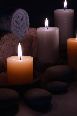 Siyah arka planda mumlar, havlular ve taşlar olan kaplıca hayatı