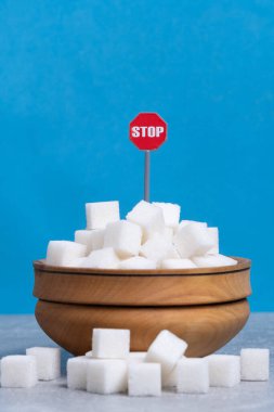 Mavi arka planda dur işareti olan tahta kasede küp şekerler.