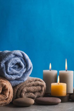 Mavi arka planda havlular, mumlar ve taşlar olan kaplıca hayatı