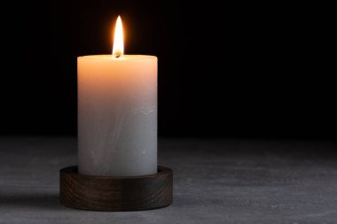 Gri masada yanan mum ve karanlık arka plan, yakın plan. Metin için yer