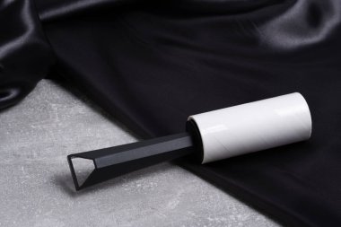 Arka plandaki siyah saten kumaş üzerindeki giysileri temizlemek için silindir