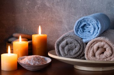 Havlular, deniz tuzu ve ahşap masadaki mumlarla dolu bir spa.