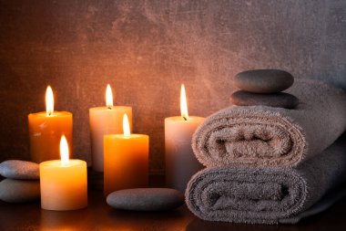Havluları, mumları ve karanlık arka planda taşları olan bir spa.