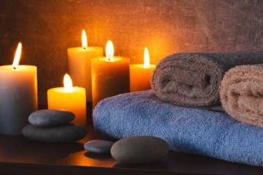 Havluları, mumları ve karanlık arka planda taşları olan bir spa.