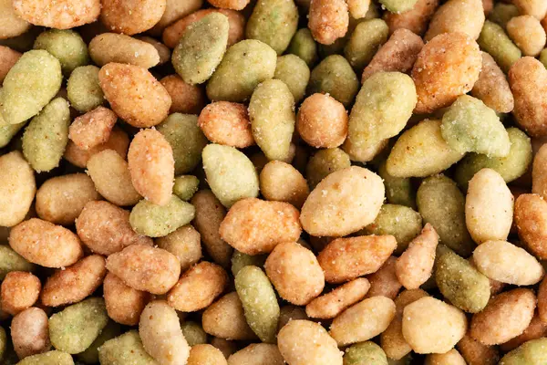 stock image Closeup side of roasted peanuts in colored glaze, which can be used as background