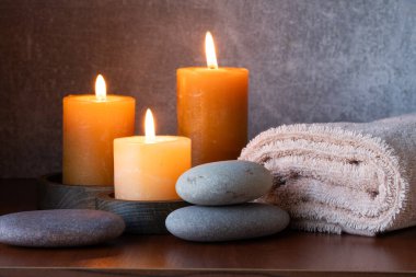 Mumlarla, havlularla ve tahta zeminde çakıl taşlarıyla dolu bir spa.