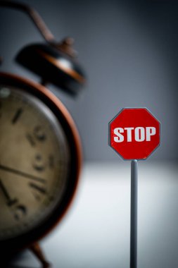Karanlık bir arka planda dur işareti ve alarm saati. Seçici odak