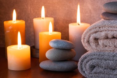 Masada mumlar, havlular ve taşlar olan bir spa.