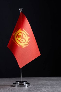 Kırgızistan bayrağı siyah arka planda metal bayrak direğine basıldı