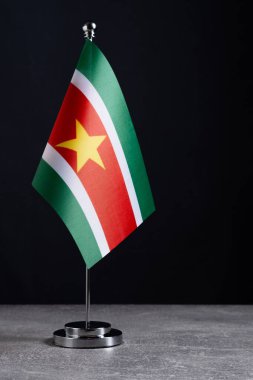 Siyah arka planda metal bayrak direğinde Surinam bayrağı. Metin için yer