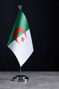 Metal üzerinde Cezayir bayrağı Gri masa üzerinde siyah arkaplan karşısında