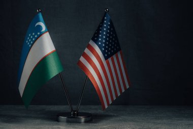 Masa bayrakları Amerika Birleşik Devletleri ve Özbekistan Ulusal Bayrağı koyu arkaplan, siyasi konsept