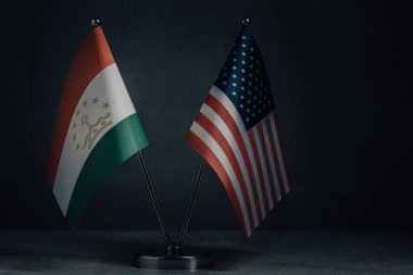 Masa bayrakları Amerika Birleşik Devletleri ve Tacikistan bayrağını koyu arka planda