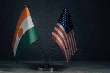 Masa bayrakları Amerika Birleşik Devletleri ve Nijer bayrağını koyu arka planda gösteriyor
