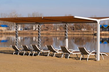 Sahilde tahta iskemleler güneşli bir bahar gölü gününde