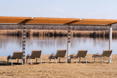 Baharın başında sahildeki gölde plaj sandalyeleri
