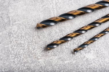 Gri beton arka planda metal matkaplar.