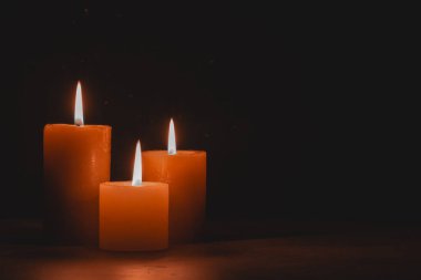 Arka plandaki siyah duvara karşı ahşap masada mum yakmak