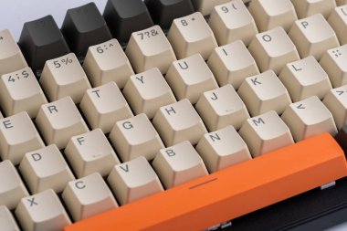 Kapalı bilgisayar klavyesinde turuncu bej ve gri tuşlar var.
