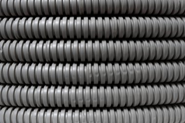 Depodaki sıra gri kıvrımlı plastik boruları tasvir eden soyut arkaplan