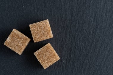 Siyah arkaplanda üç esmer şeker küpü. Kopyalama alanı olan üst görünüm