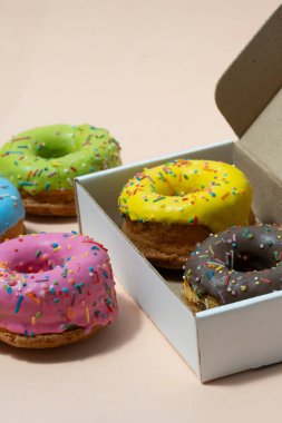 Bej arka planda hediye kutusunda renkli çörekler