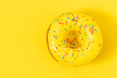 Renkli serpiştirilmiş sarı arka planda donut. Üst görünüm