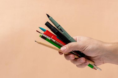 Bej arka planda eldeki kalemler ve kalemler