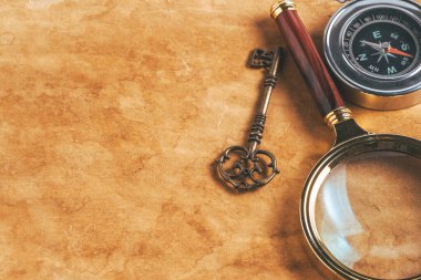 Eski kağıt zemin üzerinde vintage büyüteç, pusula ve anahtar