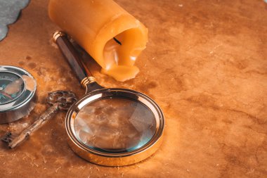 Büyüteç, anahtar, pusula ve mum arka plandaki eski kağıtlar. Seyahat kavramı