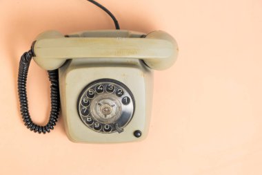Klasik bir döner telefon, eski tasarımı ve yıpranmış özelliklerini sergileyen pastel renkli bir yüzeye dayanır. Yumuşak ışıklandırma onun nostaljik çekiciliğini ve tarihini arttırır..