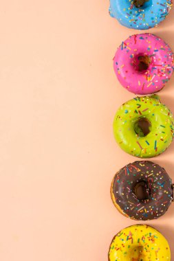 Pastel arka planda renkli çörekler. Kopyalama alanı olan üst görünüm