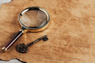 Eski kağıt arka planda büyüteç ve anahtarlar. Kopyalama alanı olan üst görünüm