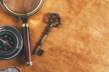 Eski kağıt zemin üzerinde antika büyüteç, pusula ve eski anahtar